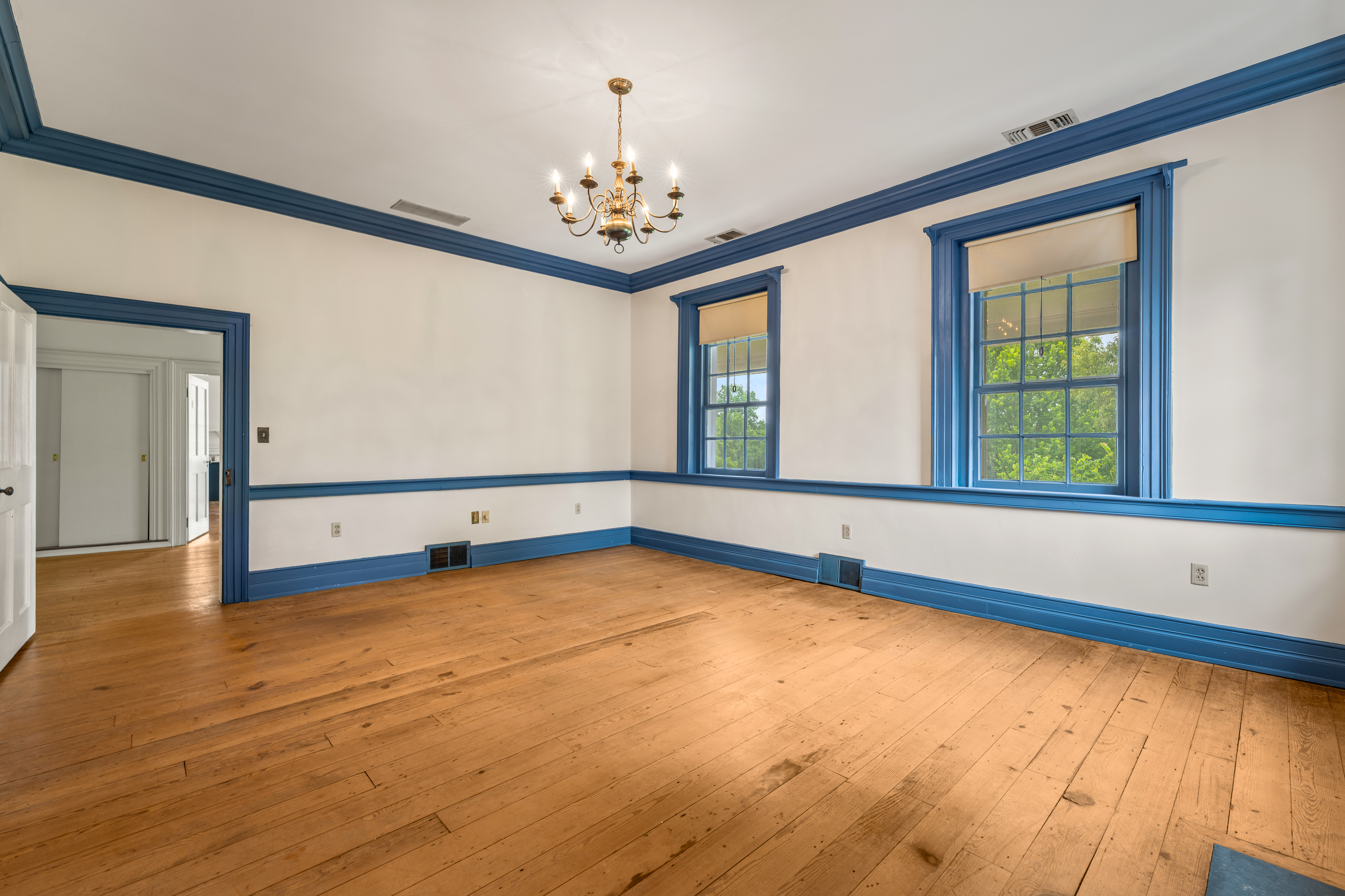 A blue-trimmed chamber with corner windows and hearth