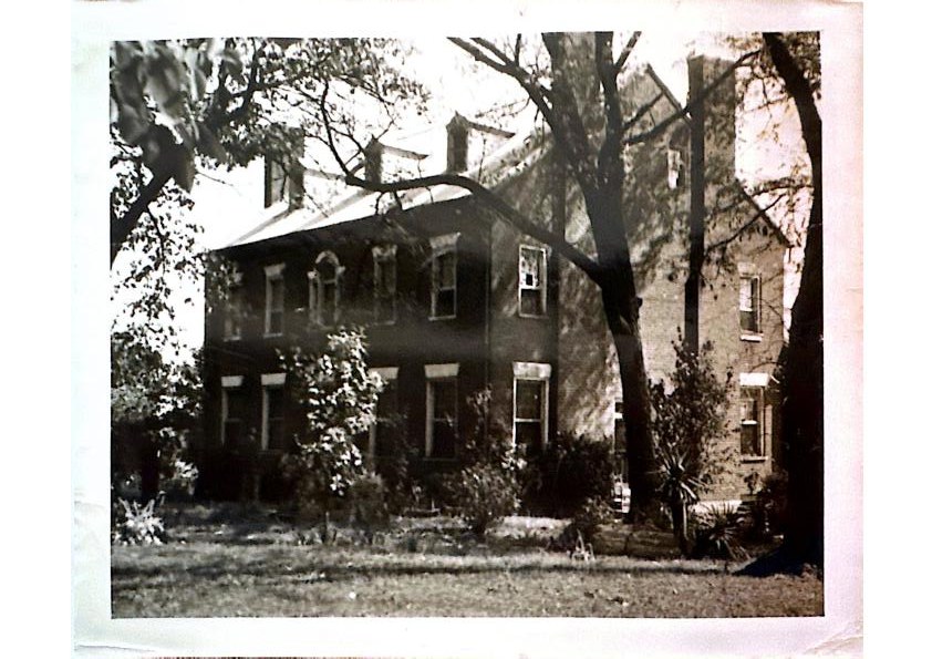 The manor at rest — brick façade among mature trees
