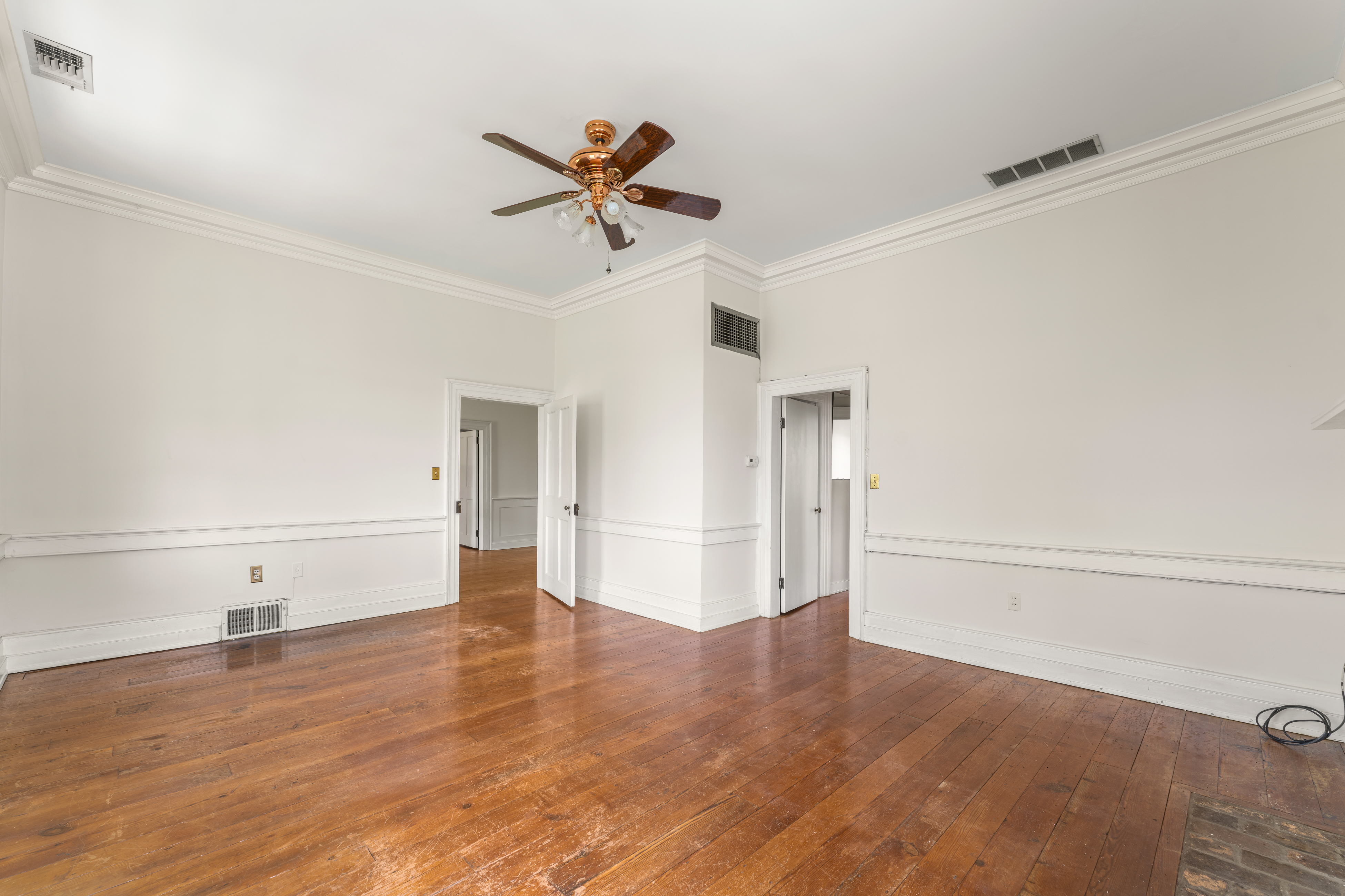 An upper chamber with wide-plank floors and paneled trim