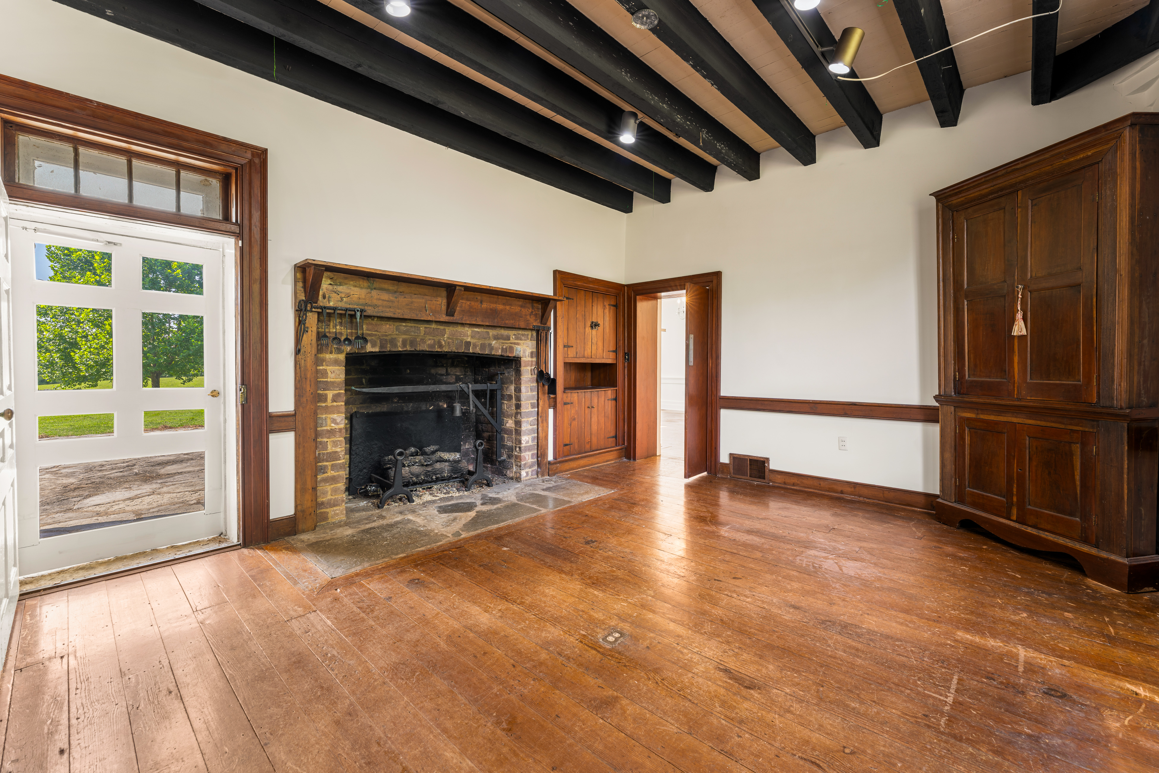 A hearth room with beamed ceiling and wide-plank floor