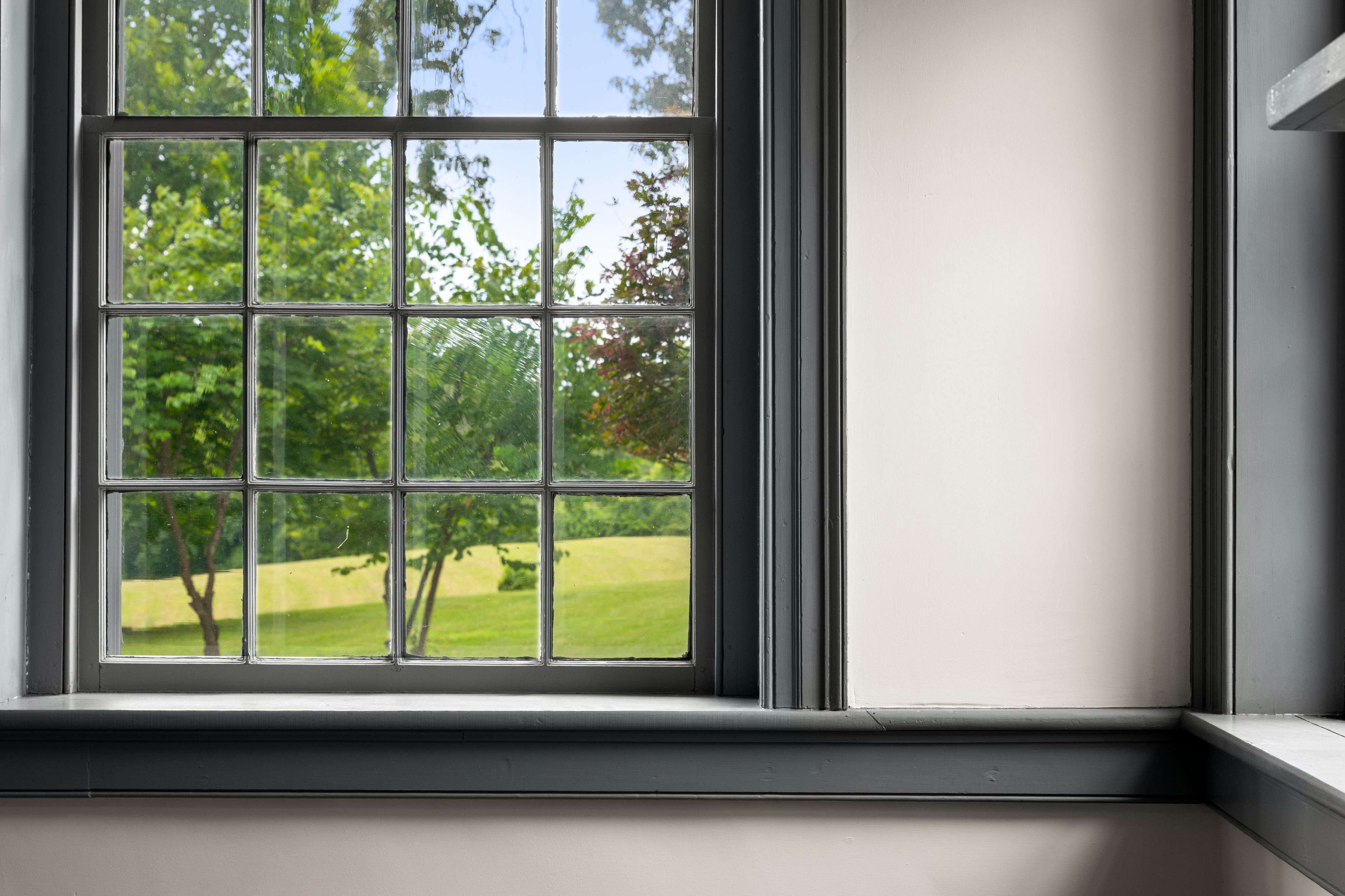 A bedchamber with tall sash windows overlooking the grounds